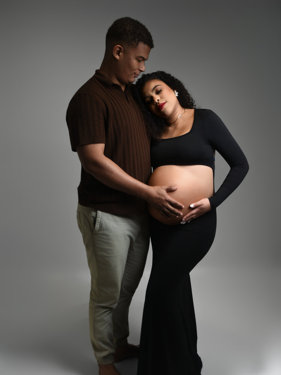 Casal abraçado em ensaio gestante, ela com a mão na barriga