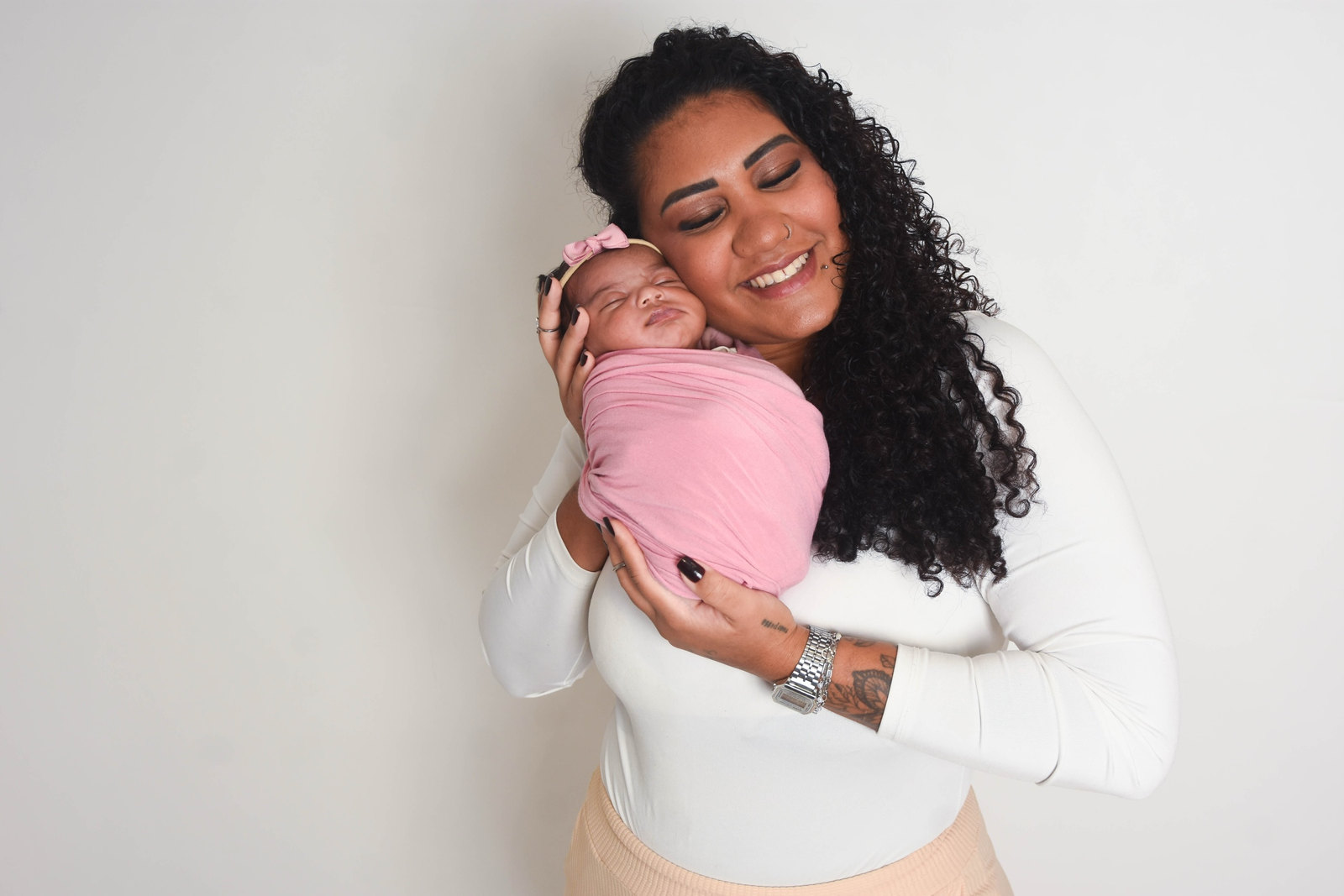 Mãe beija a filha recém-nascida enrolada em manta rosa